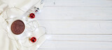 Fototapeta Nowy Jork - Cup of tea or coffee, knitted white blanket, garland and Christmas balls on wooden background. banner