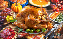 Roasted Turkey On Holiday Table With Pumpkins, Pie, Fruits, Flowers And Wine