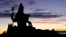 Statue Of Meditating Hindu God Shiva, Time Lapse At Twilight With Colourful Sky