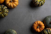 A Variety Of Different Autumnal Pumpkins And Gourds On A Dark Concrete Background