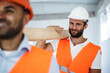 © fotofabrika - Two young men builders carrying wood planks on construction site, close up