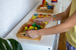 Child takes a tray of Montessori material from the shelf. Homeschooling concept.