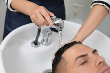 Wall Mural - Professional hairdresser washing client's hair at sink indoors, closeup