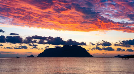 Wall Mural - Stunning view of the silhouette of Tavolara island during a dramatic sunrise with a calm water flowing in the foreground. Porto Istana, Sardinia, Italy.