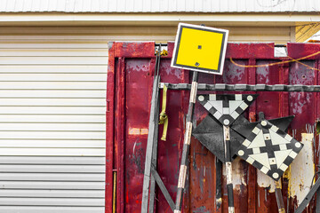 a pile of used railway signs are stacked near an old metal red booth; there is a place to insert text