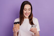 © Tetiana - Photo of young girl look read browse cellphone read morning news drink latte isolated over violet color background