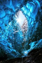Blue Glacial Ice With Hole Through To The Sky With Sun Burst, From An Ice Cave In The Glacier. Vatnajokull Glacier In Southeast Iceland.