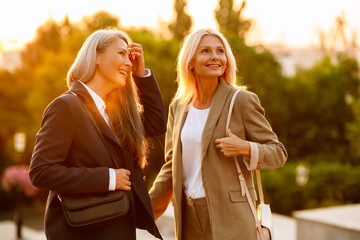 mature multiracial businesswomen smiling and talking during meeting