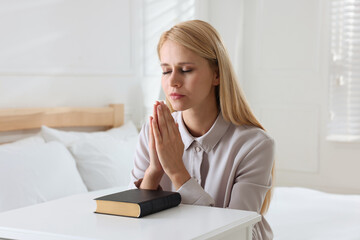 Wall Mural - Religious young woman with Bible praying in bedroom