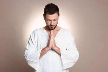 Wall Mural - Religious man with clasped hands praying against grey background