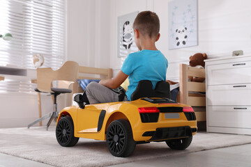 Poster - Cute little boy driving big toy car at home, back view