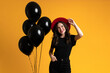 White woman in red hat smiling while posing with black balloons