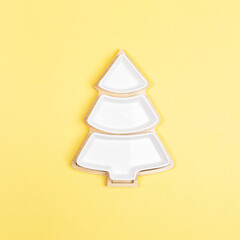 xmas festive minimal square image with empty plate in shaped of christmas tree on yellow.
