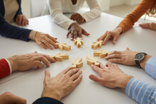 Group Of Multiethnic Business People And Teammates Sitting Around Office Table Put Little Wooden Human Figures In Circle As Symbol Of Community, Team, Help, Cooperation, Collaboration And Teamwork