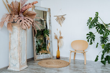  Interior shot. Bright room of the studio.A vase with piles of wheat Interesting wooden table. The main element of the room: a wicker mat. floor mirror and wooden chair.