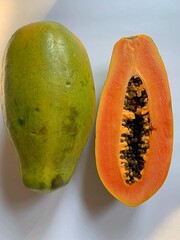 Wall Mural - ripe papaya, cut in half papaya and one whole, seeds of ripe papaya, juicy orange fruit, natural vitamins