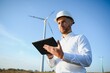 © Serhii - Young engineer man looking and checking wind turbines at field