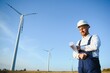 © Serhii - Engineer in wheat field checking on turbine production