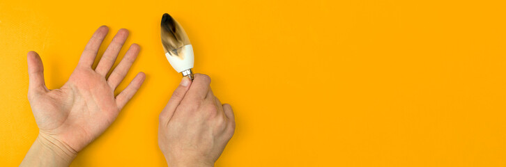 Burned LED light bulb after fire. Concept of electrical short circuit. Burning wire in house, dangerous, failure. Home safety. Top view, orange background photo