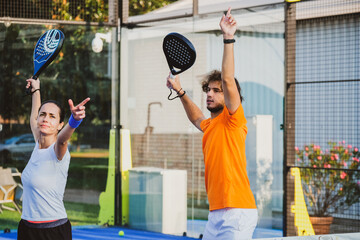 Wall Mural - Young teacher is monitoring teaching padel lesson to his student - Coach teaches girl how to play padel on the outdoor tennis court