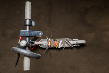 Top view of an electric scooter that is in a mechanic's workshop for repair with different types of tools on its base