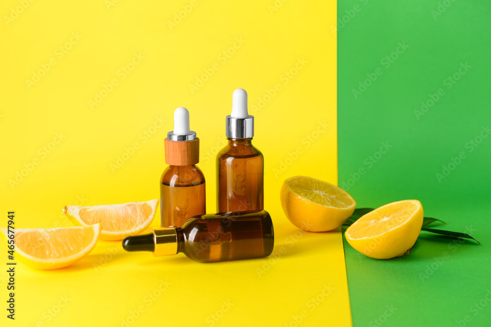 Bottles of essential oils on color background
