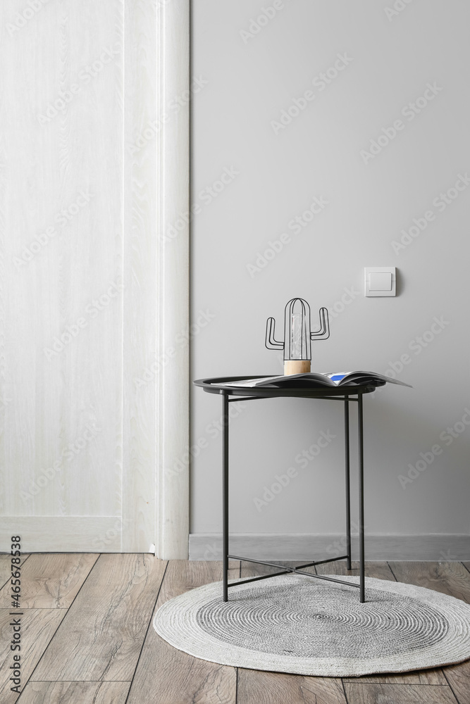 Table with lamp and magazine near light wall