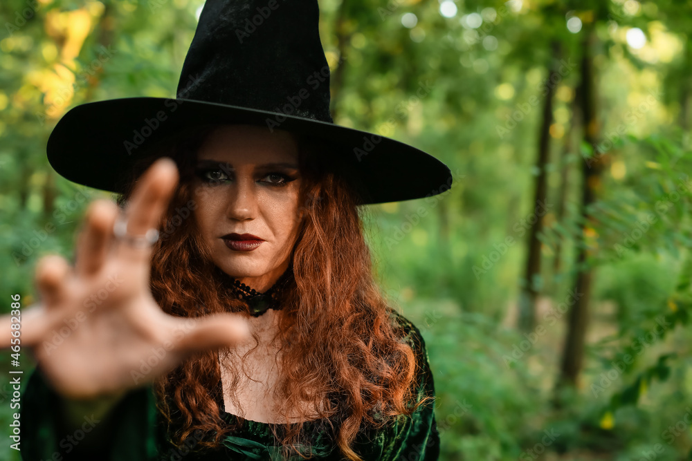 Young witch in green forest