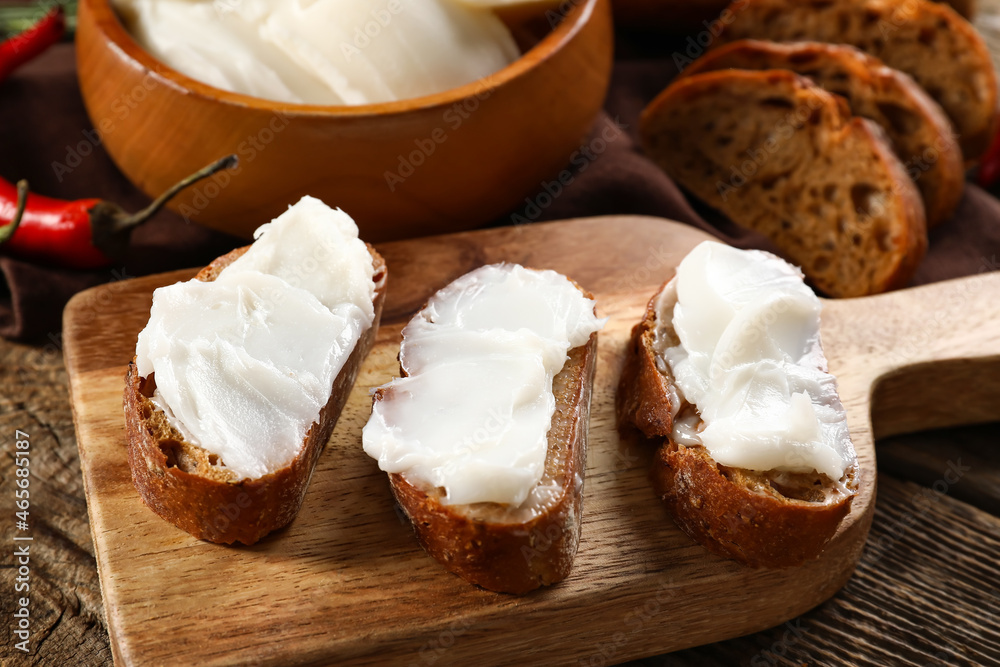 Pieces of bread with lard spread on wooden background