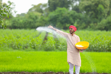 Wall Mural - Indian farmer spreading fertilizer in the green agriculture field.