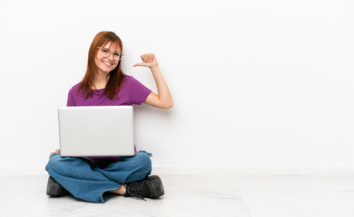 redhead girl with a laptop sitting on the floor proud and self-satisfied