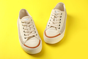 Wall Mural - Pair of beige sneakers on yellow background