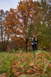 © Elena - young woman with long hair and dark clothes stands in the autumn forest among foliage and yellow trees