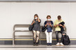 © Fran Rodríguez - A woman, a man and an older woman sitting at a subway stop looking at their cell phones wearing mask