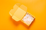 Fototapeta Lawenda - Simple yellow cardboard box on color background, empty inside with filler
