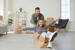 © Studio Romantic - Two young people buy house and make dream come true. Happy married couple having fun in new home on moving day. Joyful first time buyers playing with boxes in modern living room. Real estate concept
