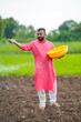 © Niks Ads - Indian farmer spreading fertilizer in the agriculture field.