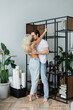 © LIGHTFIELD STUDIOS - full length of blonde woman hugging man with closed eyes near rack in living room