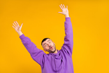 Wall Mural - Photo portrait young man wearing purple hoody amazed keeping hands up isolated vivid yellow color background