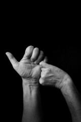 B+W image of hand demonstrating BSL sign language letter S isolated against black background