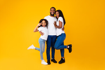 Wall Mural - African American man hugging his wife and playful daughter