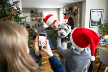 Happy Brothers And Sister With Camera Phone Putting Santa Ears On Dog