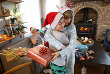 Happy Brother And Sister In Pajamas Hugging With Christmas Gift