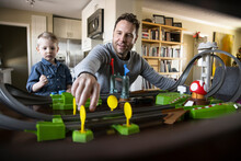 Father And Toddler Son Playing With Toy Racetrack In Living Room