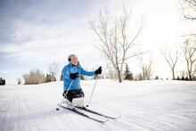 Cheerful Senior Sit-skier With Headphones Skiing In Winter