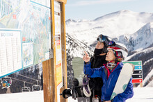 Skier And Snowboarder Planning At Ski Resort Map In Sunny Mountains