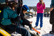 Family With Smart Phone Preparing Ski Equipment In Sunny Parking Lot