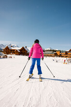 Woman Skiing Towards Sunny Ski Resort Lodge