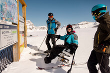 Disabled Skier And Friends Looking At Sunny Ski Resort Map