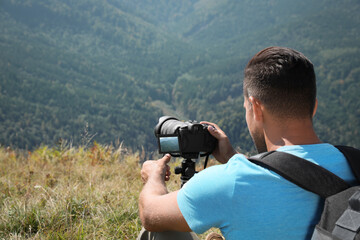 Sticker - Professional photographer taking picture with modern camera in mountains. Space for text